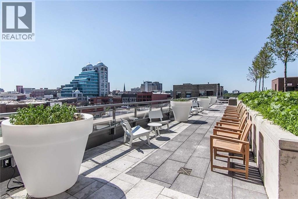Expansive rooftop terrace featuring large format paver flooring, a glass railing system, and integrated planters with greenery - 85 Duke Street W Unit# 507, Kitchener, ON - Outdoor