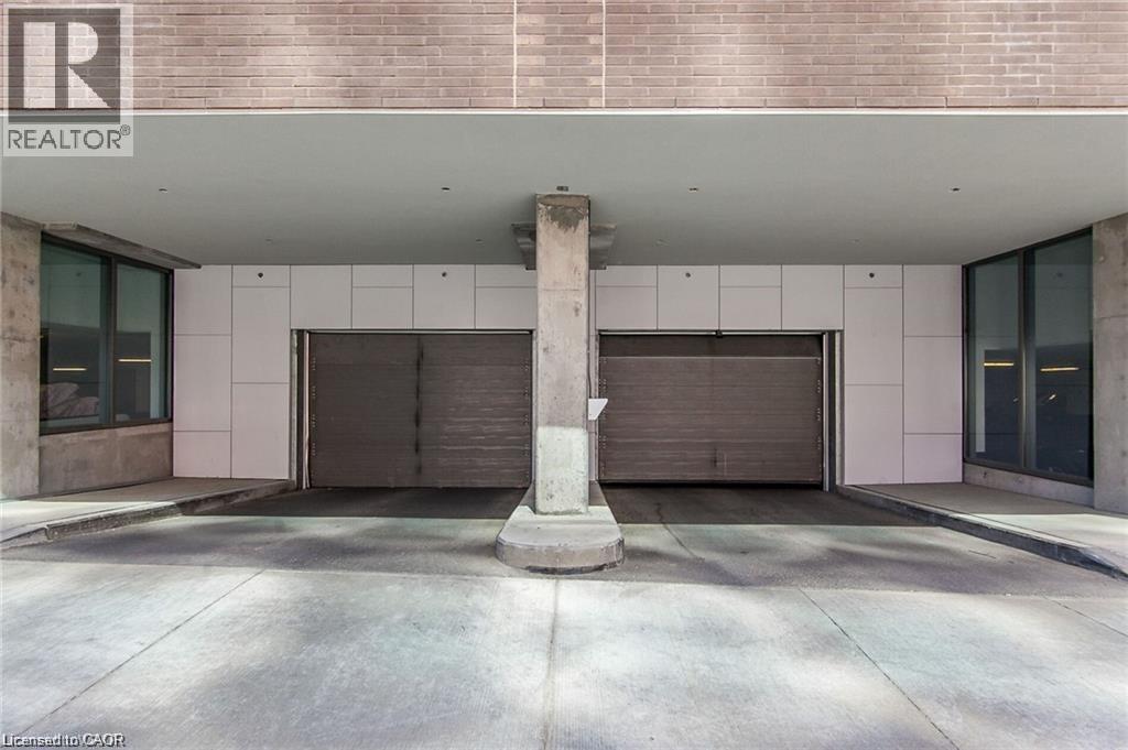 Covered parking garage featuring two roll-up doors and concrete support columns - 85 Duke Street W Unit# 507, Kitchener, ON - Indoor Photo Showing Garage