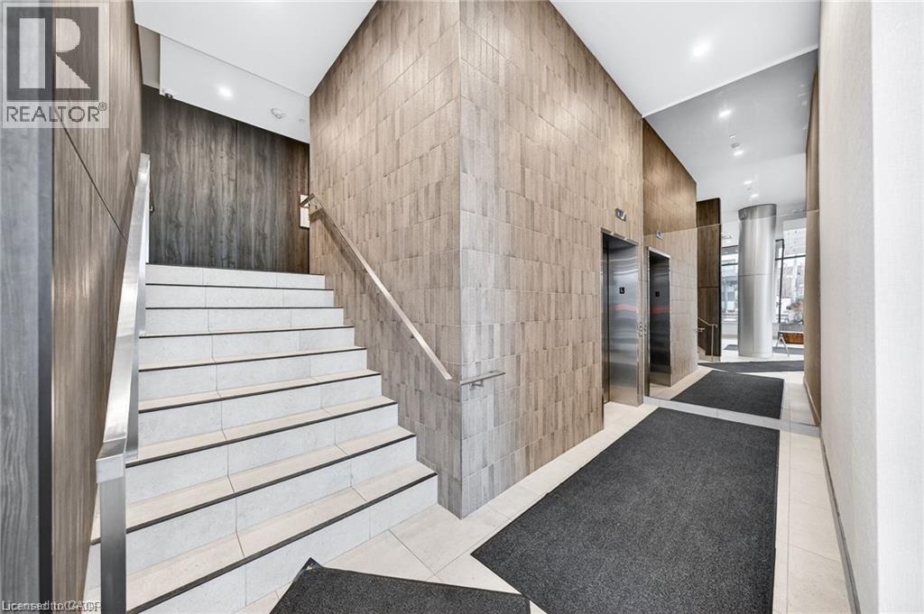 Entry foyer featuring a tiled staircase with metal handrails, two stainless steel elevators, and textured wall paneling - 85 Duke Street W Unit# 507, Kitchener, ON - Indoor Photo Showing Other Room