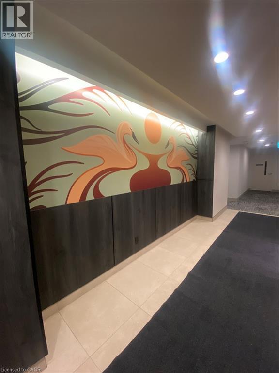 Hallway featuring a decorative mural with integrated backlighting, a dark wood-finish wainscoting, recessed ceiling lighting, and light-toned floor tiling - 85 Duke Street W Unit# 507, Kitchener, ON - Indoor