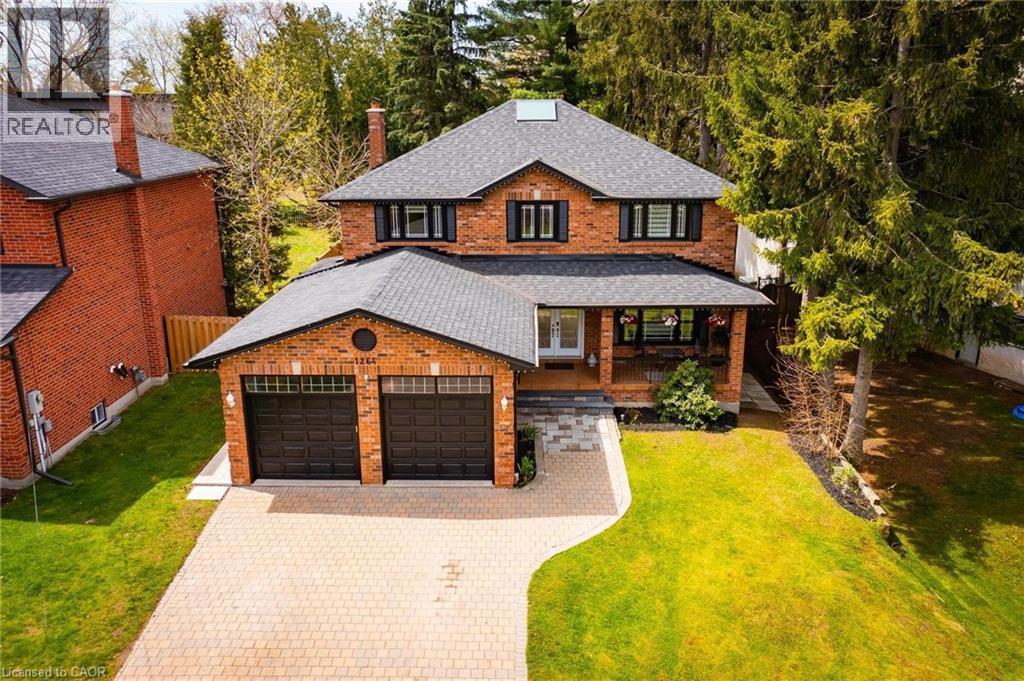 Brick-clad exterior featuring a two-car garage with black doors, a covered porch, a paver driveway, and a gabled roof - 1264 Kane Road, Mississauga, ON - Outdoor