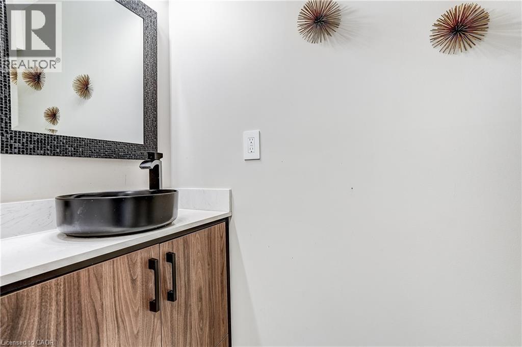 Contemporary vanity featuring a vessel sink with a matte black faucet, wood-finish cabinetry, and a light-toned countertop - 1264 Kane Road, Mississauga, ON - Indoor