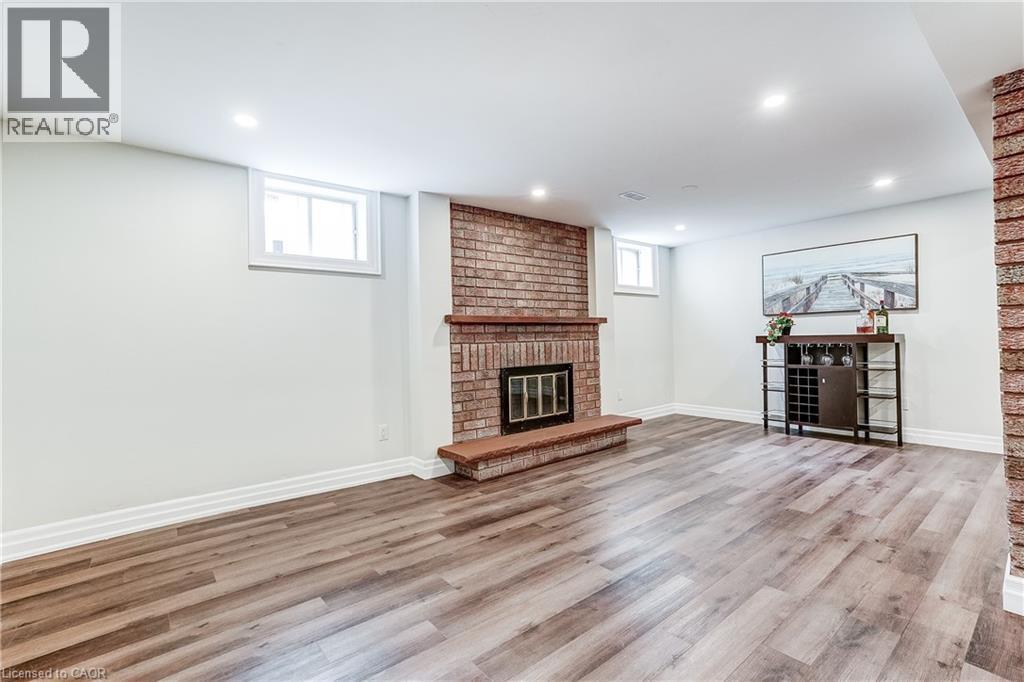 Spacious room featuring wood-finish flooring, a brick fireplace with a wood mantle, recessed lighting, and white baseboards - 1264 Kane Road, Mississauga, ON - Indoor Photo Showing Living Room With Fireplace