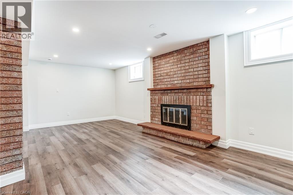 Spacious room featuring a brick fireplace with a wood mantle, wood-finish flooring, recessed lighting, and white baseboards - 1264 Kane Road, Mississauga, ON - Indoor With Fireplace