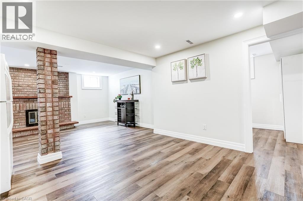 Spacious room featuring wood-finish flooring, a brick-faced fireplace, a brick column, and recessed lighting - 1264 Kane Road, Mississauga, ON - Indoor With Fireplace