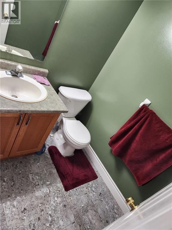 Bathroom featuring a white toilet, wood-finish vanity with a built-in sink, gray-patterned flooring, and a wall-mounted mirror - 1126 Copper Leaf Crescent, Kitchener, ON - Indoor Photo Showing Bathroom