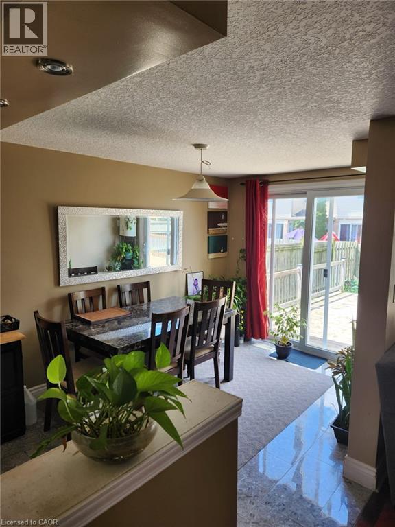 Dining area with a pendant light fixture, featuring a sliding glass door to the exterior, wood-finish dining chairs, and a large wall mirror - 1126 Copper Leaf Crescent, Kitchener, ON - Indoor