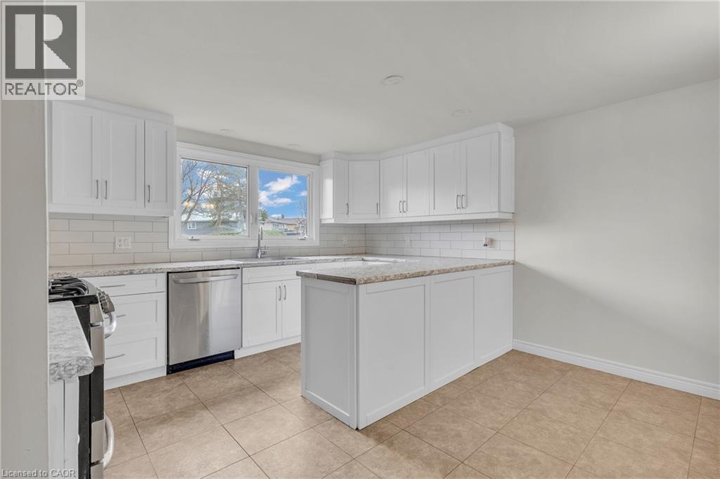 Modern kitchen featuring white shaker cabinetry, stainless steel appliances, light-toned countertops, and a subway tile backsplash - 22 Blackhorne Crescent, Kitchener, ON - Indoor Photo Showing Kitchen