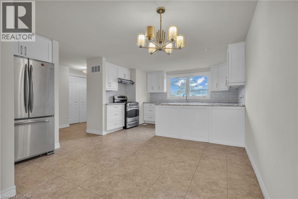 Contemporary kitchen with white cabinetry, stainless steel appliances, and a tile backsplash - 22 Blackhorne Crescent, Kitchener, ON - Indoor Photo Showing Kitchen