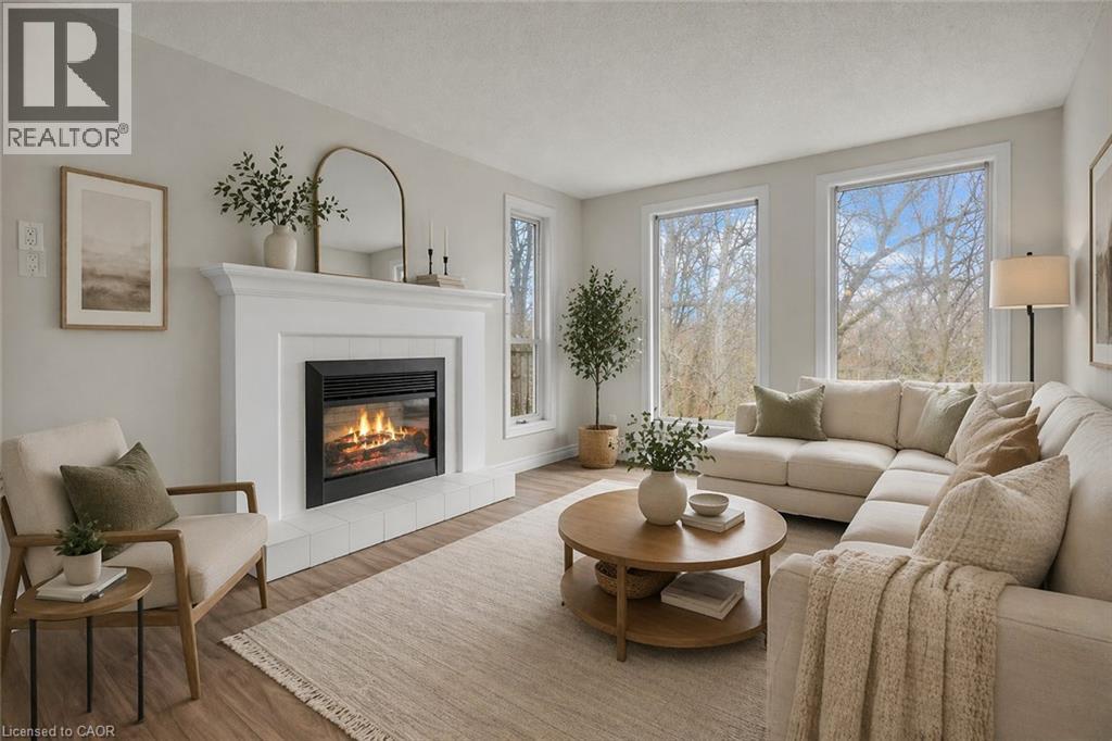 Living space featuring a white mantel fireplace with a black insert, wood-finish flooring, and multiple windows - 22 Blackhorne Crescent, Kitchener, ON - Indoor Photo Showing Living Room With Fireplace