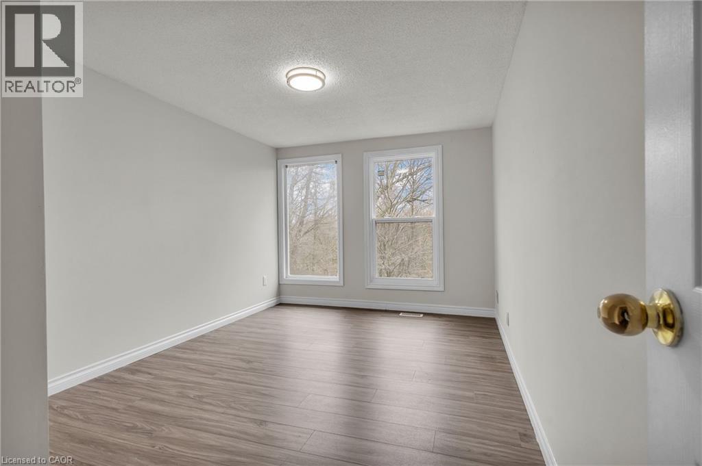 Bright interior space featuring wood-finish flooring, white baseboards, and light-toned walls - 22 Blackhorne Crescent, Kitchener, ON - Indoor Photo Showing Other Room