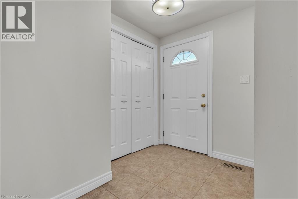 Entryway featuring neutral wall paint, tile flooring, a white paneled door with an arched glass insert, and bi-fold closet doors - 22 Blackhorne Crescent, Kitchener, ON - Indoor Photo Showing Other Room