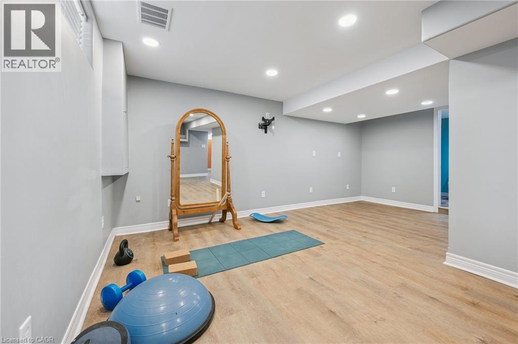 Finished lower level featuring recessed lighting, wood-finish flooring, light gray wall paint, white baseboards, and a doorway opening to an additional interior space - 838 Moore Street, Cambridge, ON - Indoor
