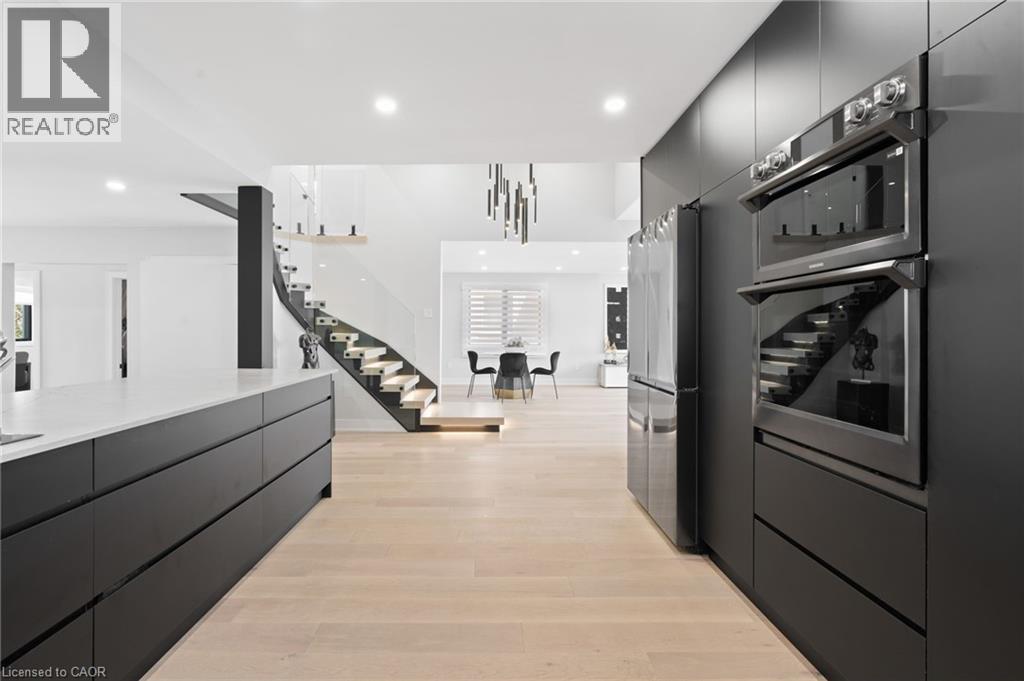 Kitchen with modern cabinets, dark cabinets, stainless steel appliances, light wood-style floors, and recessed lighting - 17 Clearview Drive, Hamilton, ON - Indoor Photo Showing Kitchen