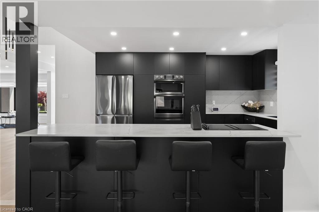 Kitchen with dark cabinetry, appliances with stainless steel finishes, a breakfast bar area, light stone countertops, and recessed lighting - 17 Clearview Drive, Hamilton, ON - Indoor Photo Showing Kitchen With Upgraded Kitchen