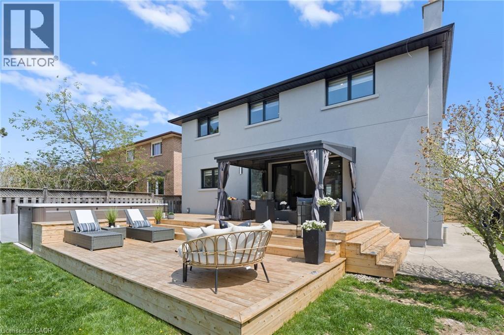 Rear view of property featuring a wooden deck, stucco siding, a yard, a chimney, and a patio area - 17 Clearview Drive, Hamilton, ON - Outdoor