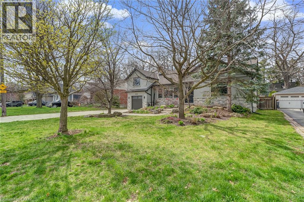 Light gray exterior with stone detailing, a prominent gabled roofline, and a driveway leading to an integrated garage - 2123 Deyncourt Drive, Burlington, ON - Outdoor