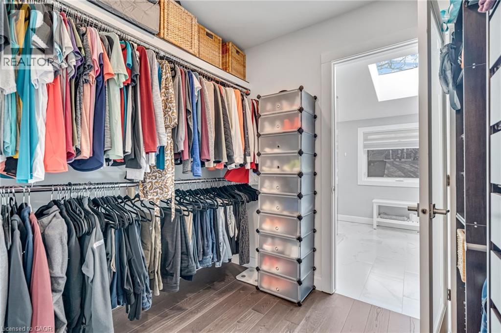 Organized walk-in closet featuring extensive hanging storage, overhead shelving, and wood-finish flooring - 2123 Deyncourt Drive, Burlington, ON - Indoor With Storage