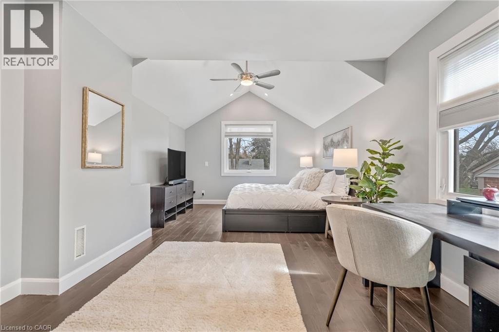 Spacious room featuring vaulted ceilings, wood-finish flooring, a contemporary ceiling fan, and two windows providing natural light - 2123 Deyncourt Drive, Burlington, ON - Indoor Photo Showing Bedroom