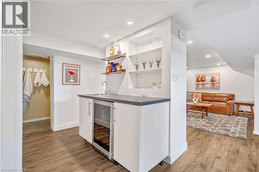 Modern wet bar featuring a stainless steel under-counter beverage cooler, white cabinetry, a sink with a chrome faucet, and integrated shelving - 2123 Deyncourt Drive, Burlington, ON - Indoor Photo Showing Other Room