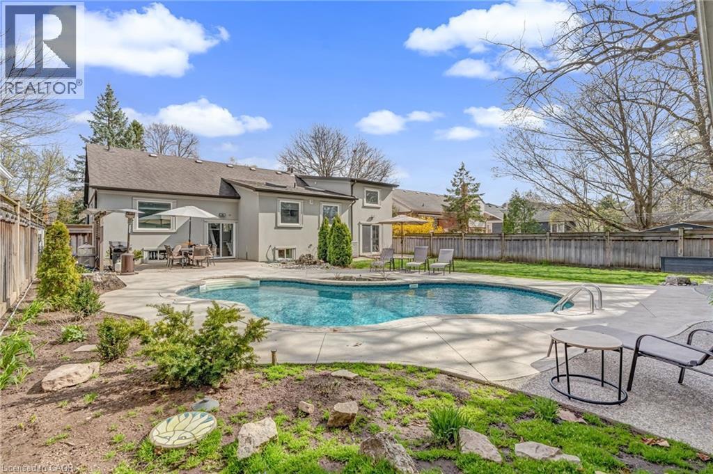 Expansive backyard featuring a large in-ground swimming pool with integrated steps, surrounded by a concrete patio - 2123 Deyncourt Drive, Burlington, ON - Outdoor With In Ground Pool With Backyard