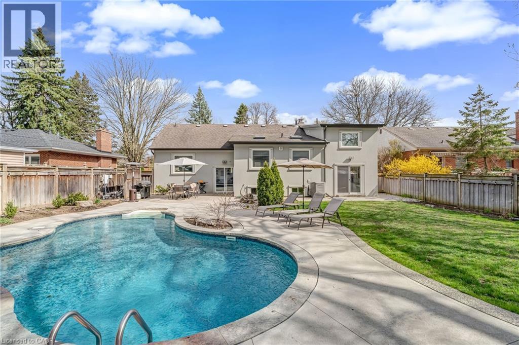 Expansive backyard featuring a freeform swimming pool with integrated steps, a stone paver patio, a manicured lawn, and mature perimeter trees - 2123 Deyncourt Drive, Burlington, ON - Outdoor With In Ground Pool With Backyard