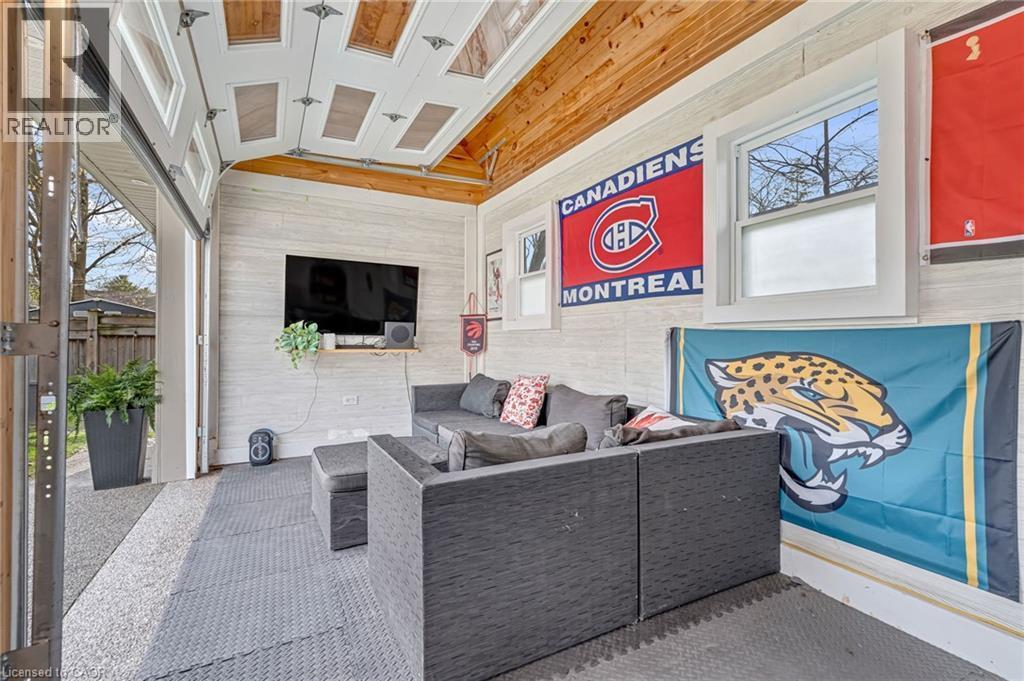 Versatile enclosed patio space featuring a paneled garage door, wood-finish ceiling, and textured wall paneling - 2123 Deyncourt Drive, Burlington, ON -