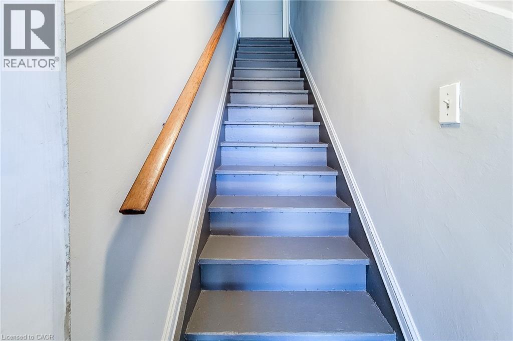 Staircase featuring painted treads and risers, a natural wood handrail, and light gray wall paint - 254 Emerald Street N Unit# Upper, Hamilton, ON - Indoor Photo Showing Other Room