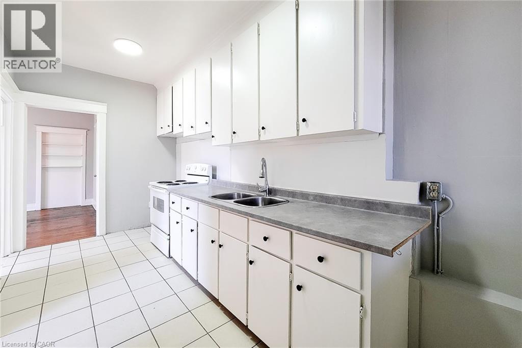 Kitchen featuring white cabinetry, a dual basin sink with chrome faucet, and a white electric range - 254 Emerald Street N Unit# Upper, Hamilton, ON - Indoor Photo Showing Kitchen With Double Sink