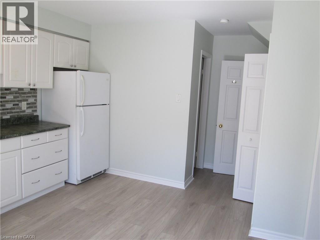 Kitchenette featuring white cabinetry, dark speckled countertops, and a mosaic tile backsplash - 648 Francis Road, Burlington, ON - Indoor