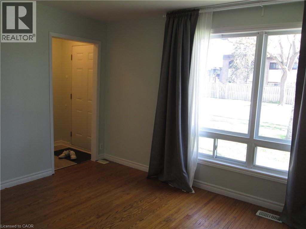 Warm wood-finish flooring complements light wall tones - 648 Francis Road, Burlington, ON - Indoor Photo Showing Other Room
