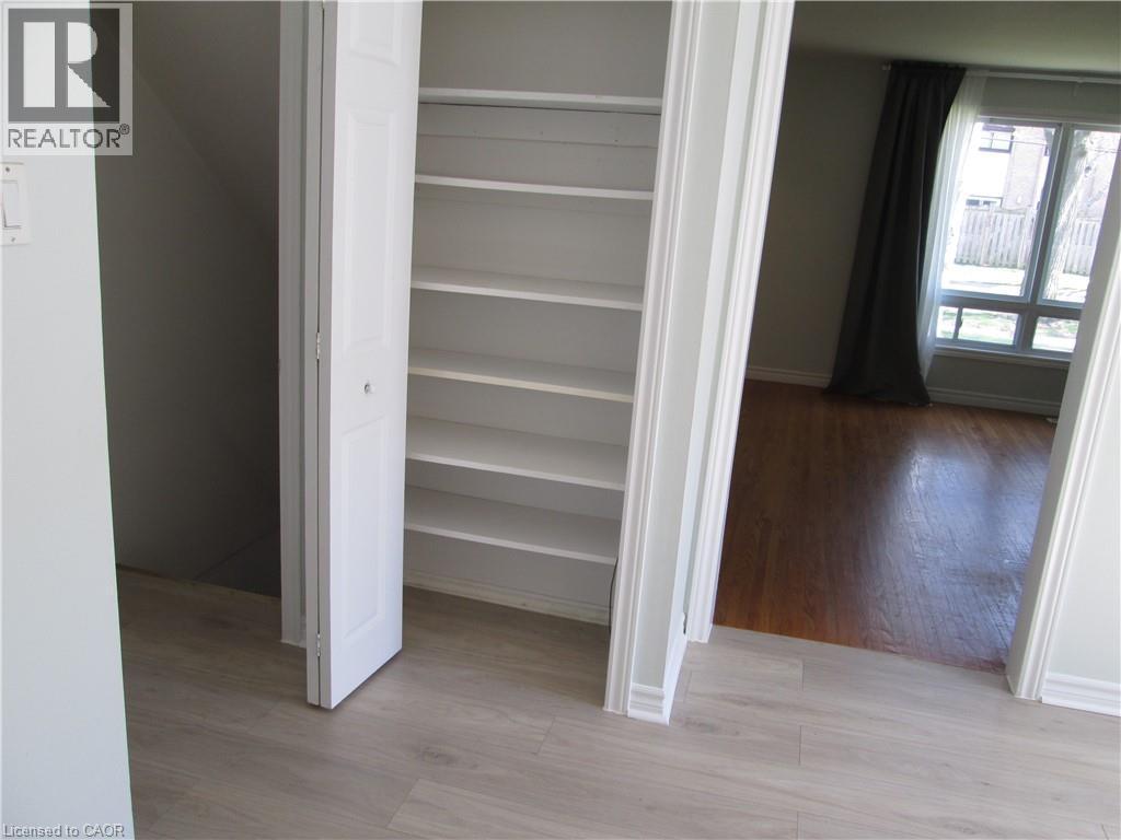 Built-in shelving unit with bi-fold doors, light wood-finish flooring, and white baseboards - 648 Francis Road, Burlington, ON - Indoor Photo Showing Other Room