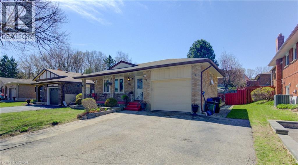 Brick-clad bungalow featuring a covered front porch with white columns, an attached garage, and a concrete driveway - 170 Martinglen Crescent, Kitchener, ON - Outdoor With Facade