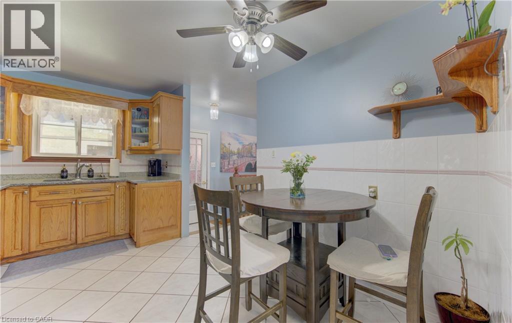 Kitchen and dining area featuring light wood cabinetry, granite-style countertops, and white tile flooring - 170 Martinglen Crescent, Kitchener, ON - Indoor Photo Showing Dining Room