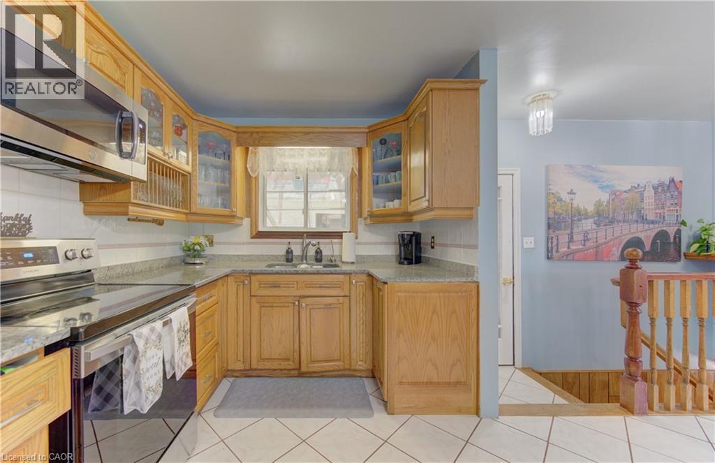 Kitchen featuring wood cabinetry, stainless steel appliances, a tile backsplash, and light-toned countertops - 170 Martinglen Crescent, Kitchener, ON - Indoor Photo Showing Kitchen