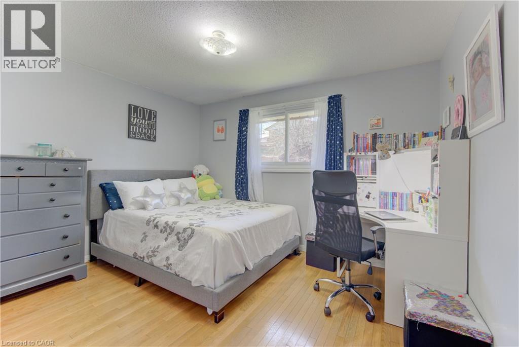 Bedroom featuring light wood-finish flooring, a window with dark blue curtains, and a built-in white desk with shelving - 170 Martinglen Crescent, Kitchener, ON - Indoor Photo Showing Bedroom