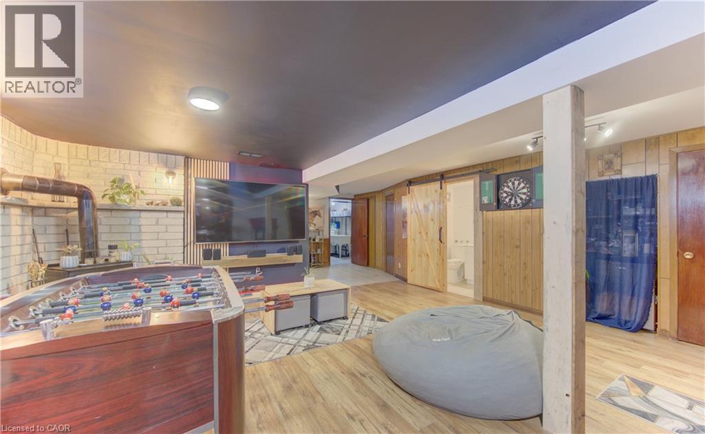 Recreation room featuring wood-finish flooring and a white brick-style wall - 170 Martinglen Crescent, Kitchener, ON - Indoor