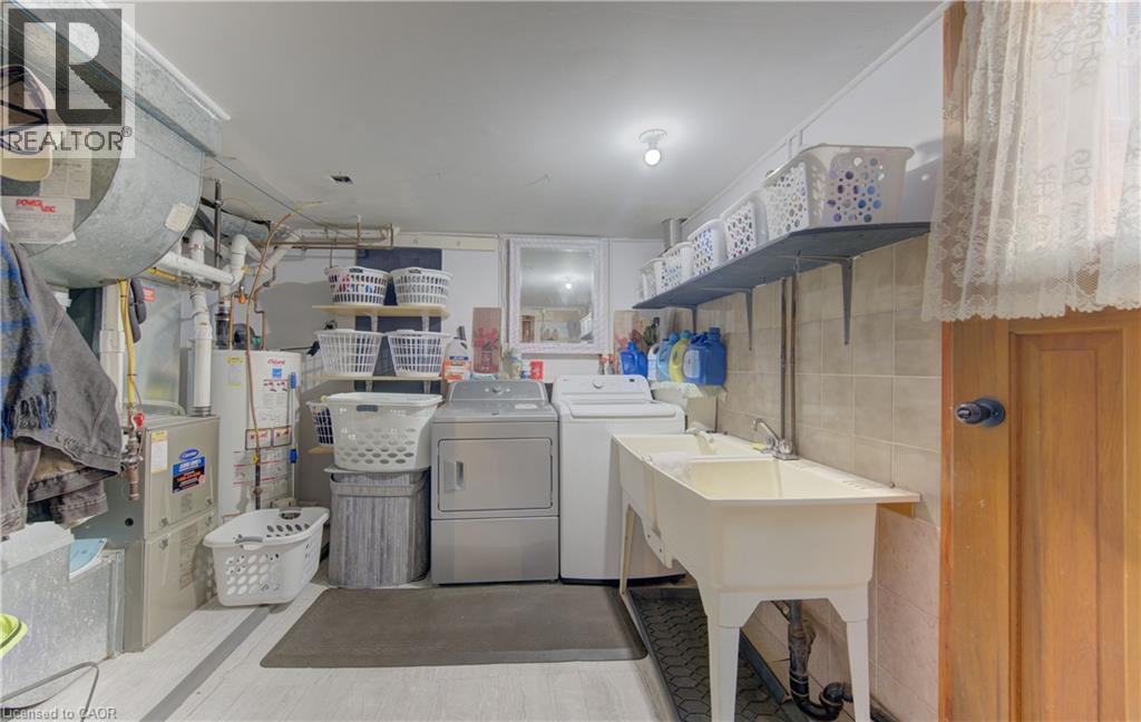 Dedicated utility area with a double basin sink, expansive wall shelving, and durable tile wainscoting - 170 Martinglen Crescent, Kitchener, ON - Indoor Photo Showing Laundry Room
