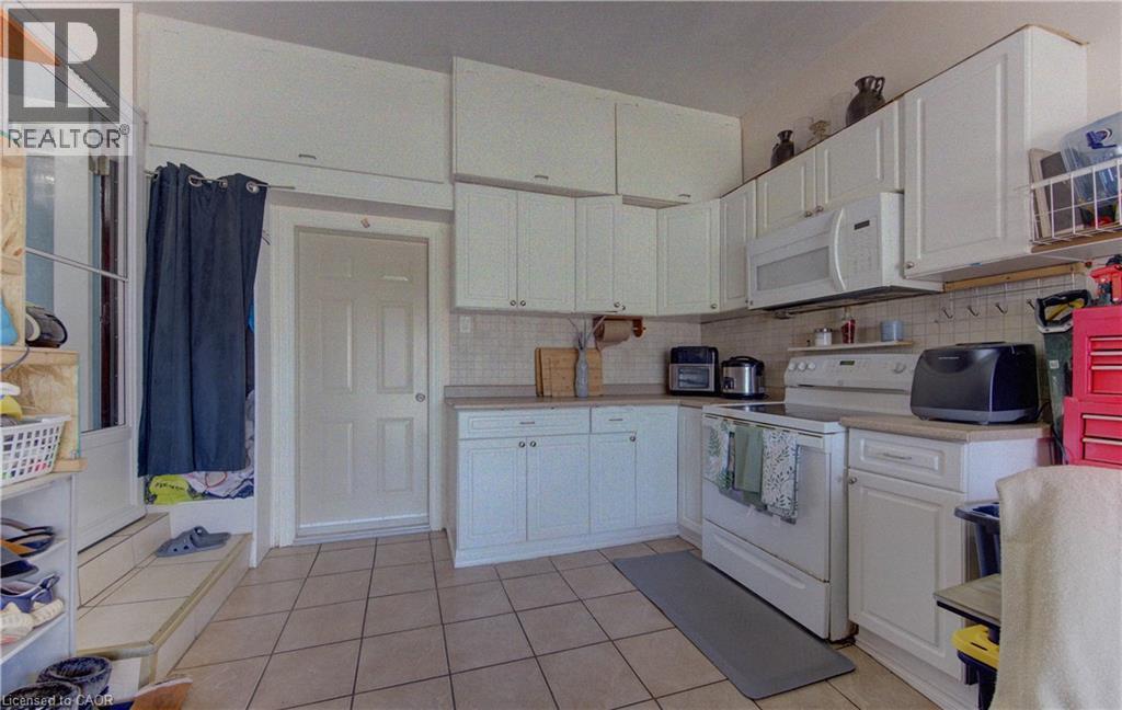Kitchen featuring extensive white cabinetry, a built-in microwave, tiled flooring, and a neutral backsplash - 170 Martinglen Crescent, Kitchener, ON - Indoor Photo Showing Kitchen