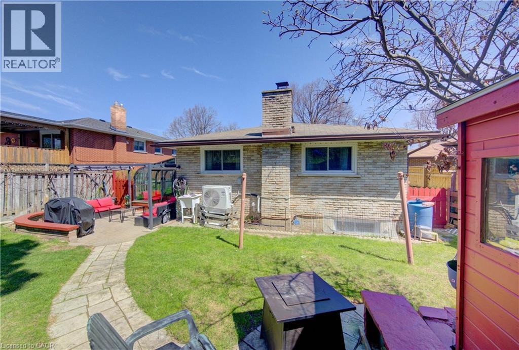 Expansive backyard featuring a stone patio, a manicured lawn, a winding stone pathway, a brick exterior, and a permanent privacy fence - 170 Martinglen Crescent, Kitchener, ON - Outdoor