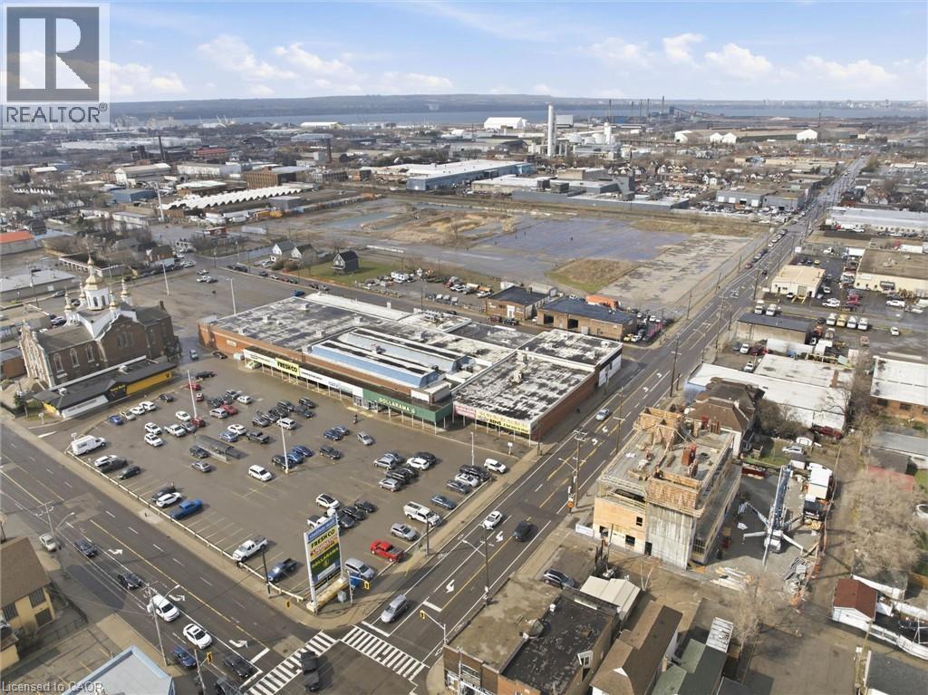 Commercial building featuring a flat roofline, extensive surface parking, and prominent street frontage - 869 Barton Street E, Hamilton, ON