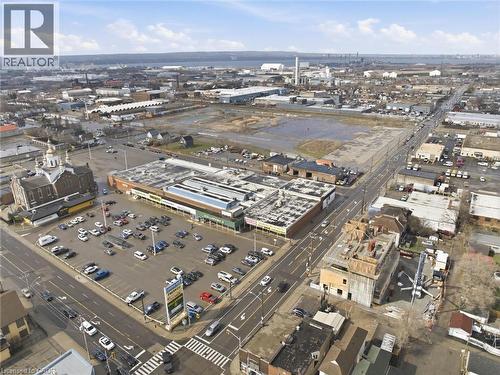 Commercial building featuring a flat roofline, extensive surface parking, and prominent street frontage - 869 Barton Street E, Hamilton, ON 