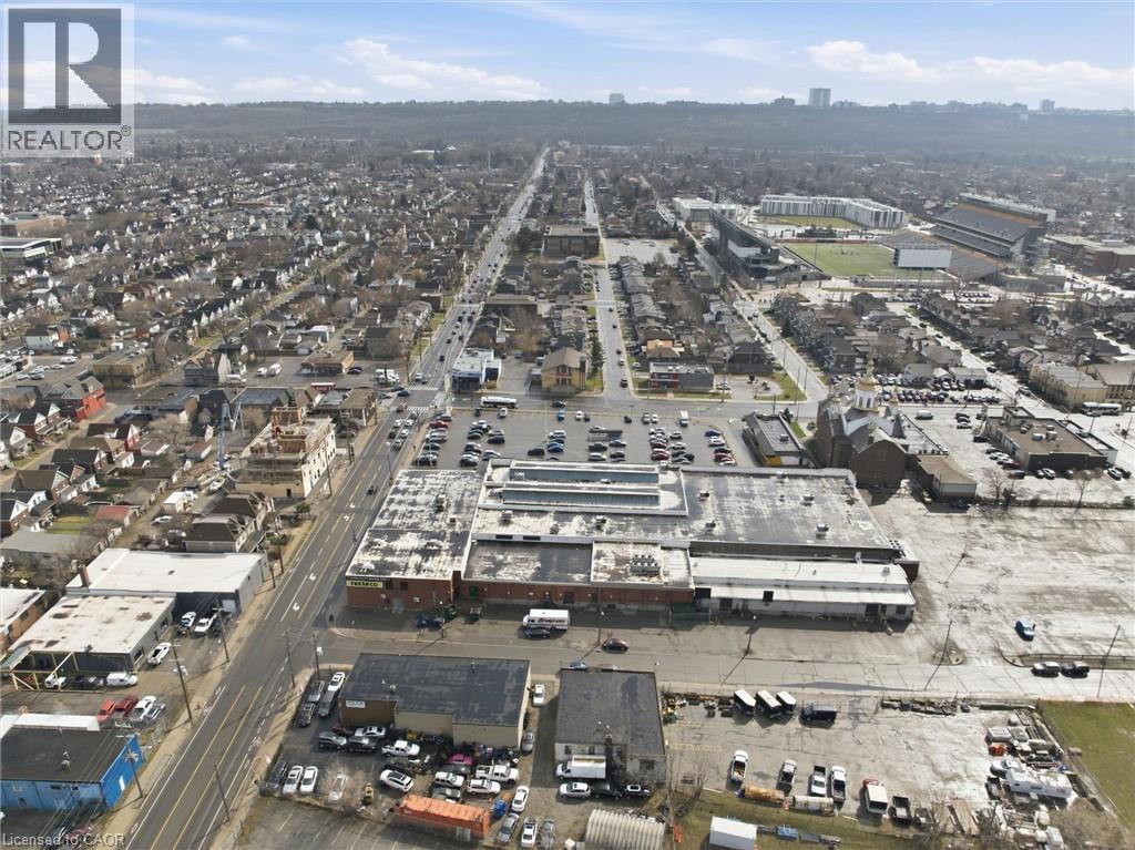 Aerial perspective showcasing a mixed-use commercial and residential district with multiple buildings and vehicular traffic - 869 Barton Street E, Hamilton, ON