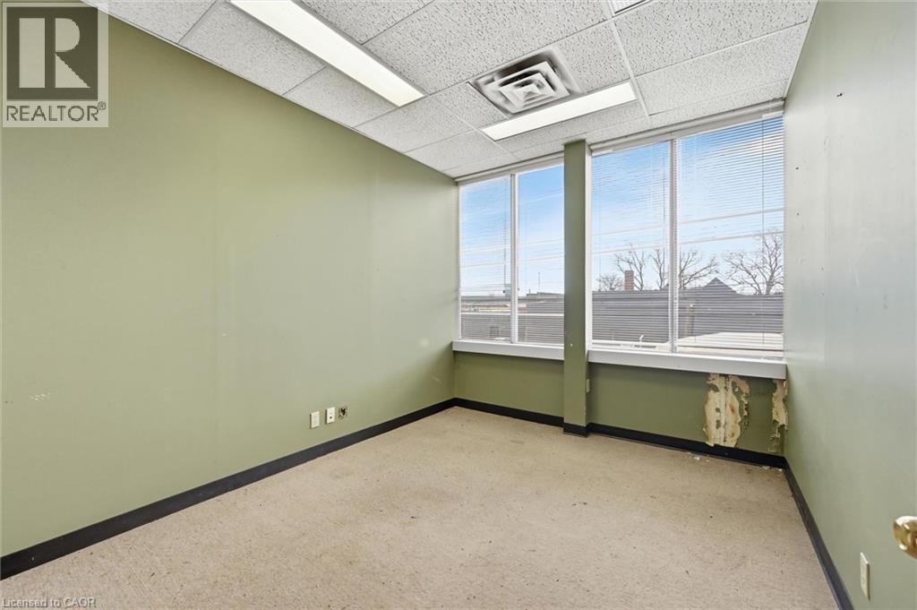 Room featuring wall-to-wall carpeting, muted green walls, and a dropped ceiling with integrated lighting - 869 Barton Street E, Hamilton, ON