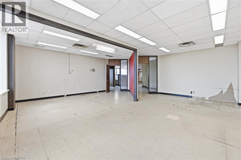 Spacious interior featuring a dropped acoustic ceiling, integrated fluorescent lighting, and a neutral-toned tile floor - 869 Barton Street E, Hamilton, ON