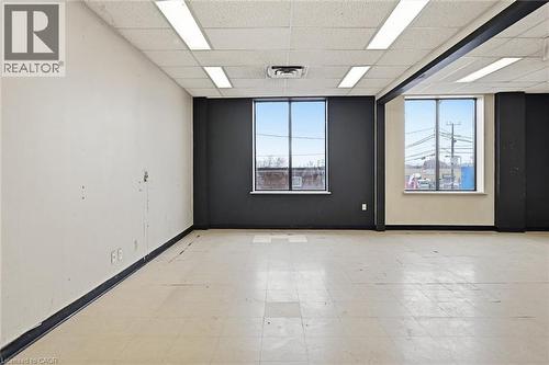 Spacious room featuring multiple large windows, recessed ceiling lighting, a suspended acoustic ceiling, and light-toned tile flooring - 869 Barton Street E, Hamilton, ON 