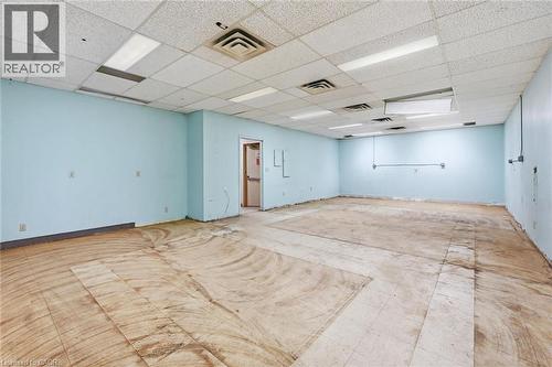 Open-concept commercial space featuring light blue walls and a dropped ceiling with integrated fluorescent lighting - 869 Barton Street E, Hamilton, ON 