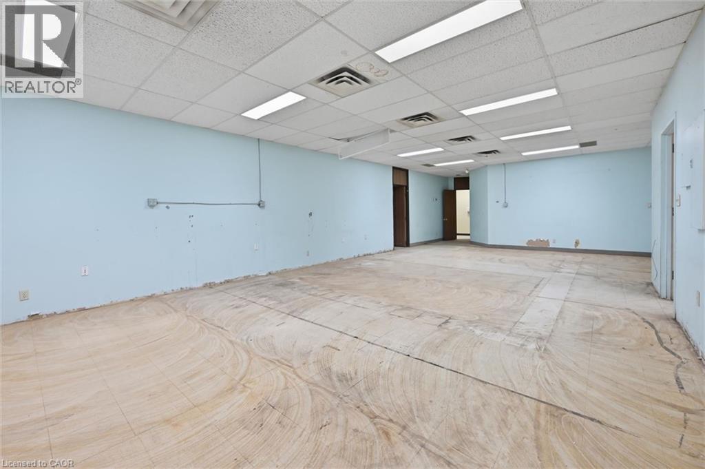 Expansive open-plan commercial space featuring light blue walls and a suspended acoustic tile ceiling - 869 Barton Street E, Hamilton, ON