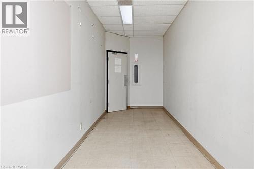 Corridor featuring light-toned square floor tiling, white painted walls, and a dropped ceiling with recessed fluorescent lighting - 869 Barton Street E, Hamilton, ON 