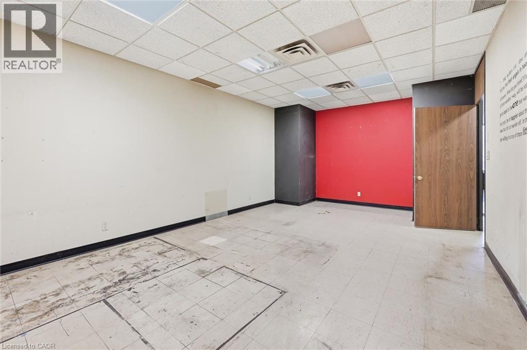 Spacious room featuring a vibrant accent wall, acoustic tile ceiling, recessed lighting, and wood-finish door - 869 Barton Street E, Hamilton, ON